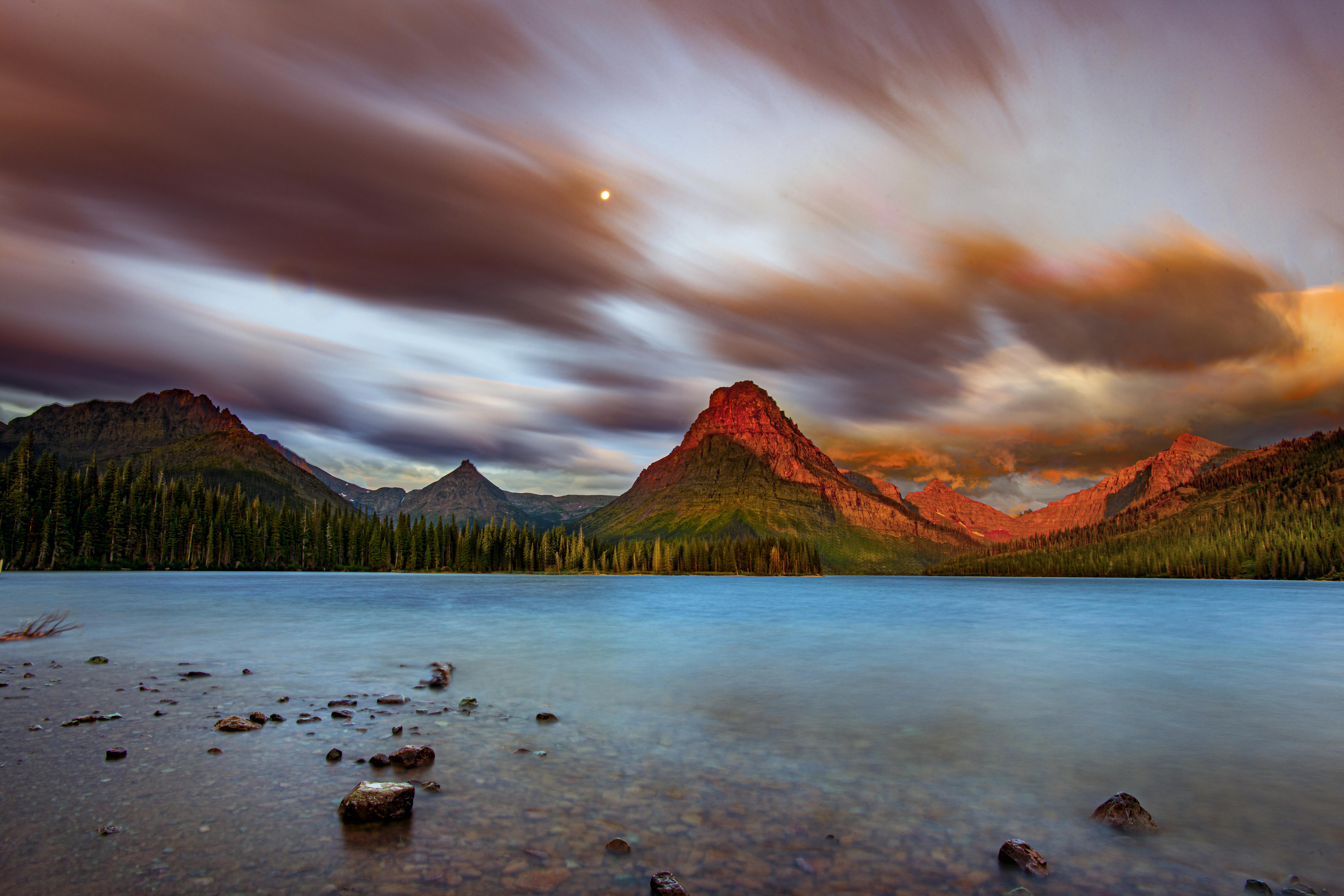 Mountain landscape surrounding Two Medicine Lake with water, forest, and peaks, fine art photograph